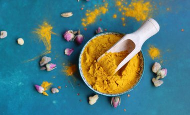 Mavi arka planda bir kasede zerdeçal tozu, üst manzara.