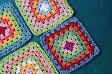 Mavi arka planda büyükanne kareleri. Kopyalama alanı olan üst görünüm. El yapımı tığ işi, örgü işi ve el işi konsepti - tığ işi aksesuarlar