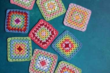 Mavi arka planda büyükanne kareleri. Kopyalama alanı olan üst görünüm. El yapımı tığ işi, örgü işi ve el işi konsepti - tığ işi aksesuarlar