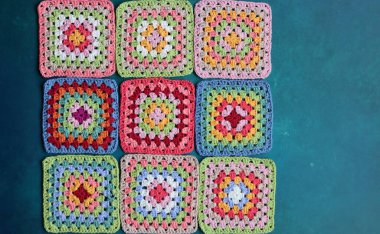 Mavi arka planda büyükanne kareleri. Kopyalama alanı olan üst görünüm. El yapımı tığ işi, örgü işi ve el işi konsepti - tığ işi aksesuarlar