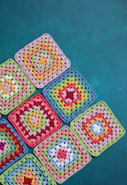 Mavi arka planda büyükanne kareleri. Kopyalama alanı olan üst görünüm. El yapımı tığ işi, örgü işi ve el işi konsepti - tığ işi aksesuarlar
