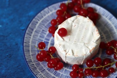 Mavi tabakta üzümlü peynirli Camembert peyniri. Fransız peynirinin yakın plan fotoğrafı..  