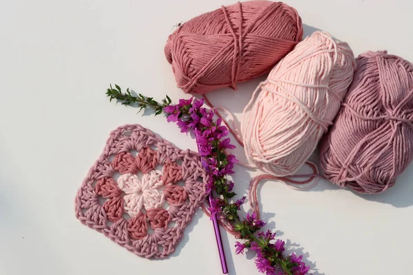 ピンクは 異なるピンク色の色合いの柔らかい綿糸ボールのおばあちゃんの正方形を編みました コピースペース付きの白い背景 スプリングクロチェットコンセプト — ストック写真
