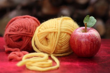 Fotokopi çekilen kırmızı arka planda balkabakları, elmalar ve ipliklerle dolu bir sonbahar. Sonbahar tığ işi fikirleri. Konforlu ev kavramı. 