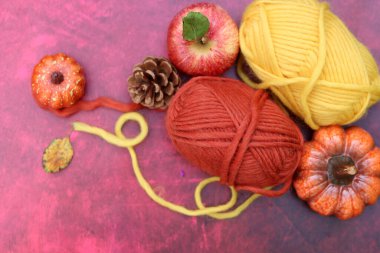 Sonbahar tığ işi. Yün yumakları, elmalar, kabaklar ve kırmızı arkaplanda fotokopi alanı olan yapraklar. Sıcaklık konsepti. 