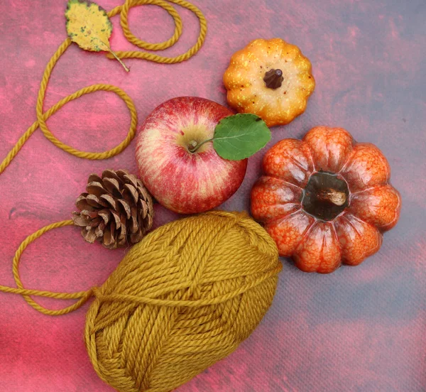 Cozy autumn still life with red apples and woolen yarn balls. Hobby and leisure concept.