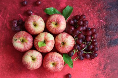 Kırmızı arka planda yaprakları olan kırmızı elmalar. Üst manzara, düz uzanma
