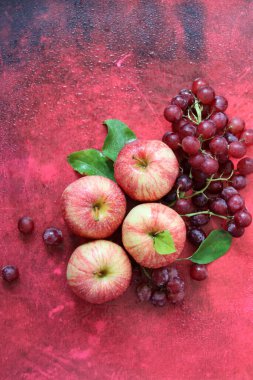 Kırmızı arka planda yaprakları olan kırmızı elmalar. Üst manzara, düz uzanma