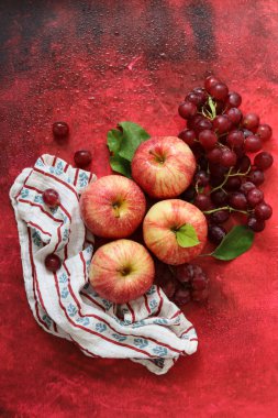 Kırmızı arka planda yaprakları olan kırmızı elmalar. Üst manzara, düz uzanma