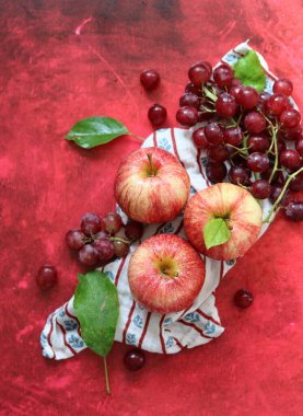 Kırmızı arka planda yaprakları olan kırmızı elmalar. Üst manzara, düz uzanma