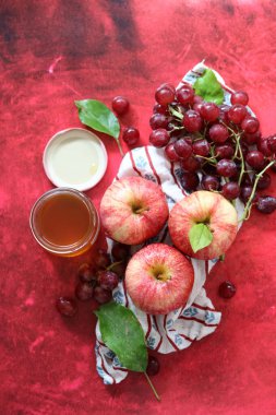 Sonbahar, kırmızı desenli arka planda olgun elma ve üzümlerle dolu bir hayattır. Üst görünüm.