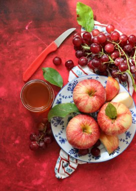 Kırmızı arka planda yaprakları olan kırmızı elmalar. Üst manzara, düz uzanma