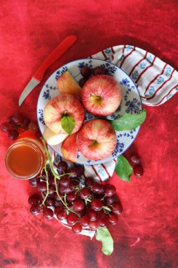Üzüm ve elmalarla dokulu kırmızı arka planda hayat dolu metin için yer var. Sağlıklı yeme kavramı. 