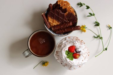 Krem şantili, beyaz arka planda kremalı ve çilekli bir fincan sıcak çikolata. Tatlı yemek konsepti. 