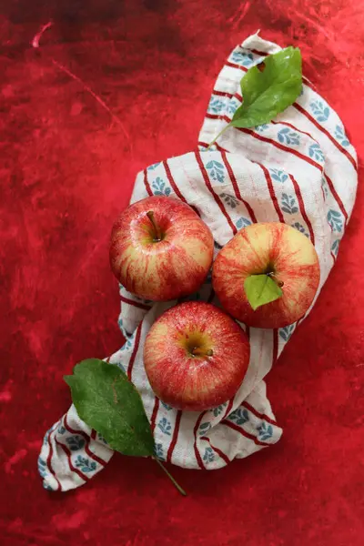 Red apples with leaves on red background. Top view, flat lay