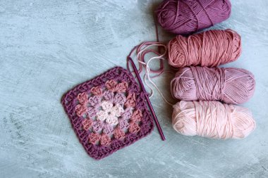 Yumuşak organik pamuktan yapılmış büyükanne kare deseni. Fotokopi alanı olan gri arkaplan. Bahar tığ işi fikirleri. 