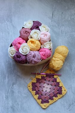 Yumuşak organik pamuktan yapılmış büyükanne kare deseni. Fotokopi alanı olan gri arkaplan. Bahar tığ işi fikirleri. 