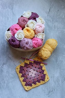 Yumuşak organik pamuktan yapılmış büyükanne kare deseni. Fotokopi alanı olan gri arkaplan. Bahar tığ işi fikirleri. 