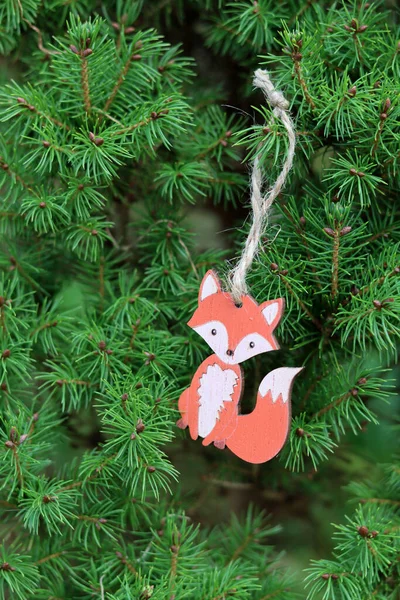 Wooden fox toy hanging on Christmas tree branch. Environmentally friendly Christmas decoration.