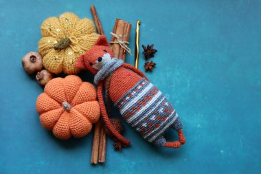 Örülmüş oyuncak tilki, iplik yumakları ve güz süslemeleri gri bir arka planda, yazı için yeri var. Sevimli amigurumi oyuncağı.. 