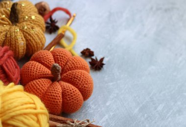 Sonbahar örgü örüyor. Örgü iğneleri, yün iplikler, anason, tarçın, açık gri arka planda örülmüş balkabağı yazı için boşluk. Şükran Günü fikirleri sunar.  