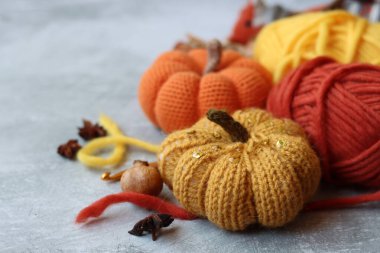 Sonbahar örgü örüyor. Örgü iğneleri, yün iplikler, anason, tarçın, açık gri arka planda örülmüş balkabağı yazı için boşluk. Şükran Günü fikirleri sunar.  