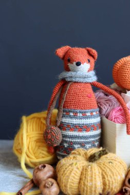 Örülmüş oyuncak tilki, iplik yumakları ve güz süslemeleri gri bir arka planda, yazı için yeri var. Sevimli amigurumi oyuncağı.. 