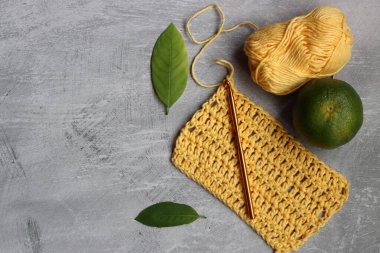 Sarı tığ işi DIY projesi. Fotokopi alanı olan gri arkaplanda organik pamuk ipliği