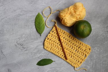 Sarı tığ işi DIY projesi. Fotokopi alanı olan gri arkaplanda organik pamuk ipliği