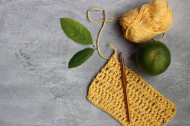 Sarı tığ işi DIY projesi. Fotokopi alanı olan gri arkaplanda organik pamuk ipliği