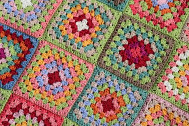 Renkli büyükanne kareleri tığ işi desenli yakın çekim fotoğrafı. Organik pamuktan yapılmış güzel bir süs. Hobiler ve eğlence konsepti. 