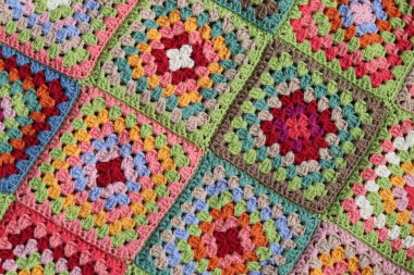 Renkli büyükanne kareleri tığ işi desenli yakın çekim fotoğrafı. Organik pamuktan yapılmış güzel bir süs. Hobiler ve eğlence konsepti. 