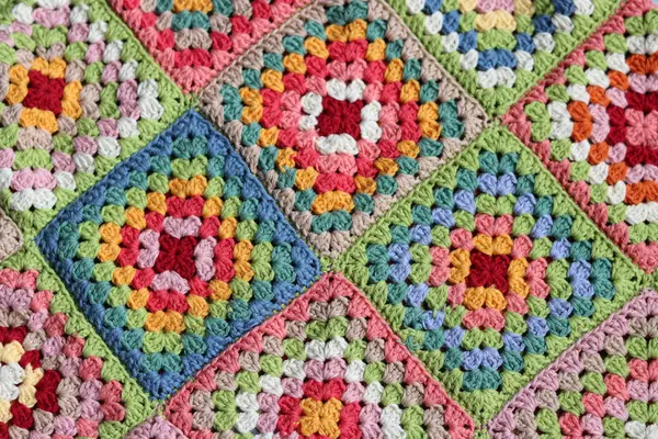 Colorful granny squares Crochet pattern close up photo. Beautiful ornament made of organic cotton yarn. Hobbies and leisure concept.