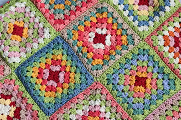 Colorful granny squares Crochet pattern close up photo. Beautiful ornament made of organic cotton yarn. Hobbies and leisure concept.