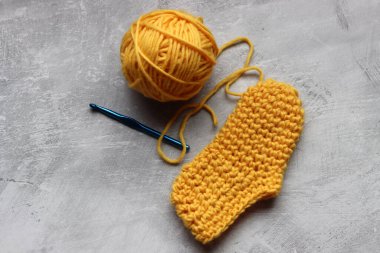 Fotokopi alanı olan gri bir arka planda bebek paçası ve sarı yün bir top. El yapımı terlikler. Fotoğrafı kapat.. 