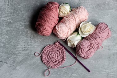 İplik yumakları, örgü iğneleri ve gri arka planda beyaz güller fotokopi alanı ile. DIY projesi devam ediyor. 