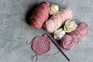 İplik yumakları, örgü iğneleri ve gri arka planda beyaz güller fotokopi alanı ile. DIY projesi devam ediyor. 