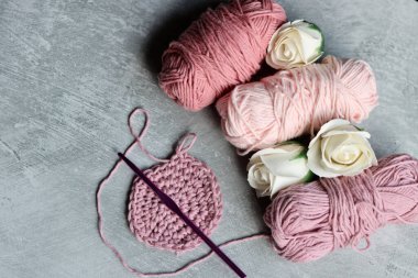 İplik yumakları, örgü iğneleri ve gri arka planda beyaz güller fotokopi alanı ile. DIY projesi devam ediyor. 