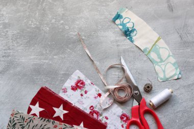 Makas, renkli kumaş, makara, bant, ölçü bandı ve fotokopi hızıyla gri arkaplana kıyafet dikmek için düğmeler. 