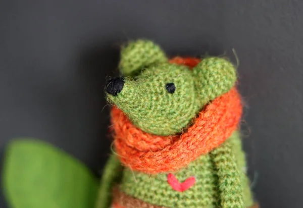 Crochet Amigurumi toy close up photo on dark grey background with copy space. Green mouse with orange scarf. Cute handmade gift.