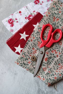 Makas, renkli kumaş, makara, bant, ölçü bandı ve fotokopi hızıyla gri arkaplana kıyafet dikmek için düğmeler. 