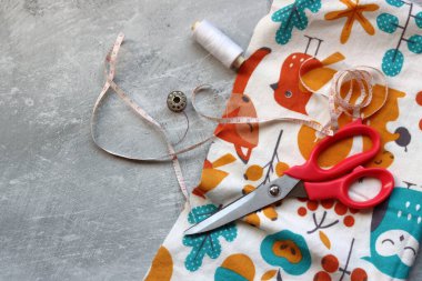 Yumuşak flanel kumaştan bir elbise dikmek, işlem aşamasında. Fotokopi alanı olan gri bir arka planda dikiş aletleri ve aksesuarları dikiyorum. Hobiler ve el sanatları konsepti. 