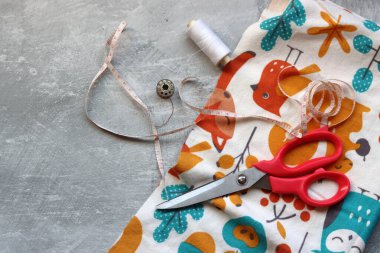 Dikiş araçları: makas, iplik, kumaş, iğne, düğme ve gri arkaplan üzerinde renkli yumuşak pamuk kumaş fotokopi alanı düz bileşimi dikiş aksesuarları 