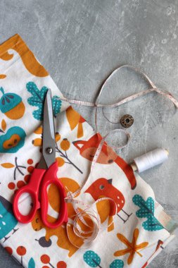 Yumuşak flanel kumaştan bir elbise dikmek, işlem aşamasında. Fotokopi alanı olan gri bir arka planda dikiş aletleri ve aksesuarları dikiyorum. Hobiler ve el sanatları konsepti. 