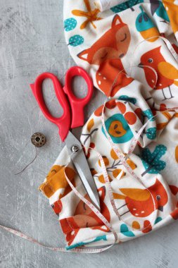 Dikiş araçları: makas, iplik, kumaş, iğne, düğme ve gri arkaplan üzerinde renkli yumuşak pamuk kumaş fotokopi alanı düz bileşimi dikiş aksesuarları 