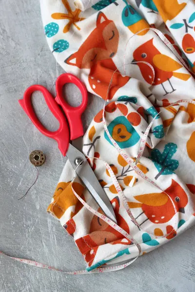 Dikiş araçları: makas, iplik, kumaş, iğne, düğme ve gri arkaplan üzerinde renkli yumuşak pamuk kumaş fotokopi alanı düz bileşimi dikiş aksesuarları 