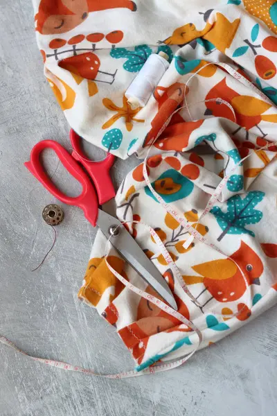 Dikiş araçları: makas, iplik, kumaş, iğne, düğme ve gri arkaplan üzerinde renkli yumuşak pamuk kumaş fotokopi alanı düz bileşimi dikiş aksesuarları 