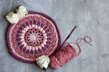 Pembe organik iplikten örülmüş trivet. Gri arkaplanda el yapımı tığ tutacağı ve metin için boşluk. 