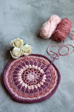 Pembe organik iplikten örülmüş trivet. Gri arkaplanda el yapımı tığ tutacağı ve metin için boşluk. 