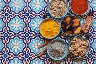 Still life with Traditional oriental spices, nuts, herbs and dried fruit on blue tiled background. Healthy eating concept. 